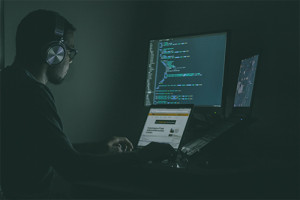 Image of a guy writing computer code in a dark room.