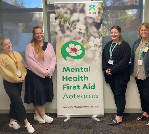 Courtney Bromwich, Danielle Botha, Mikaela Walsh and Michelle Dunn standing next to a Mental Helath First Aid banner.