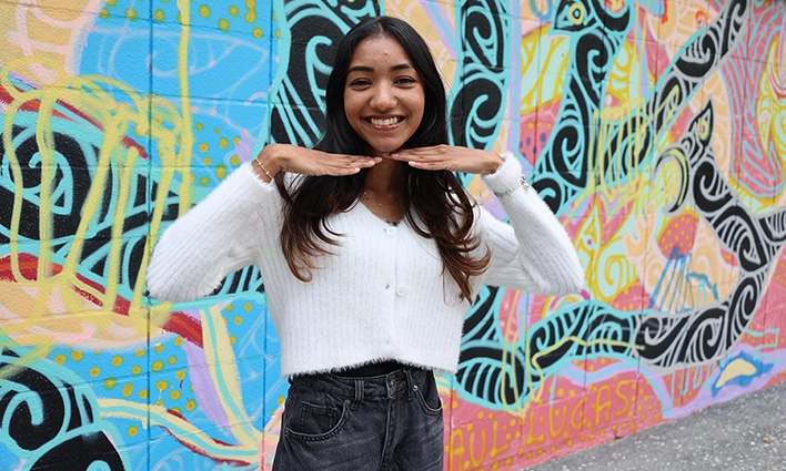 International student ambassador Nikita in front of graffitti wall