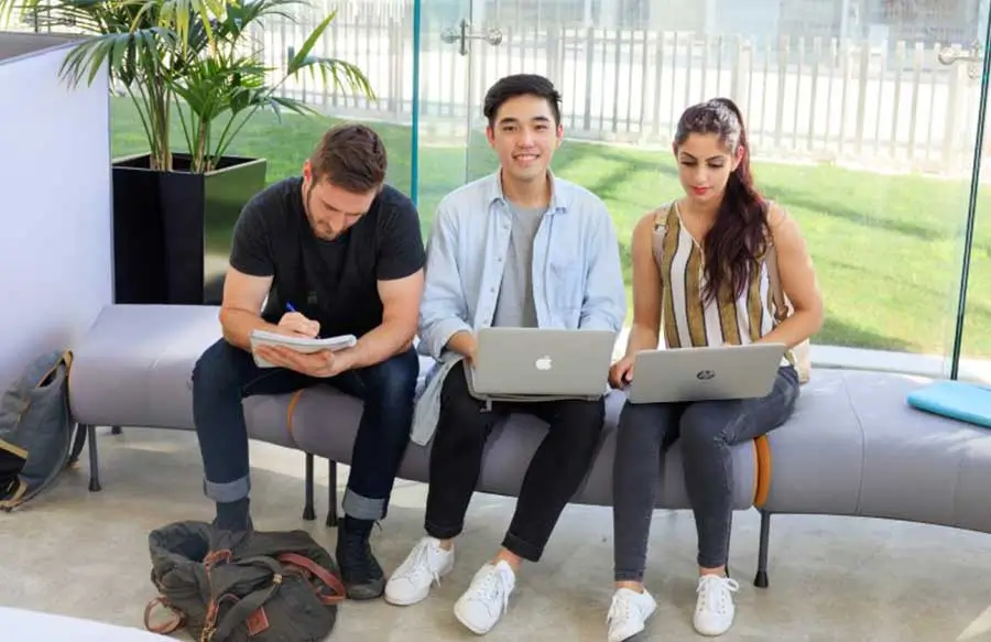 three students sitting on a couch