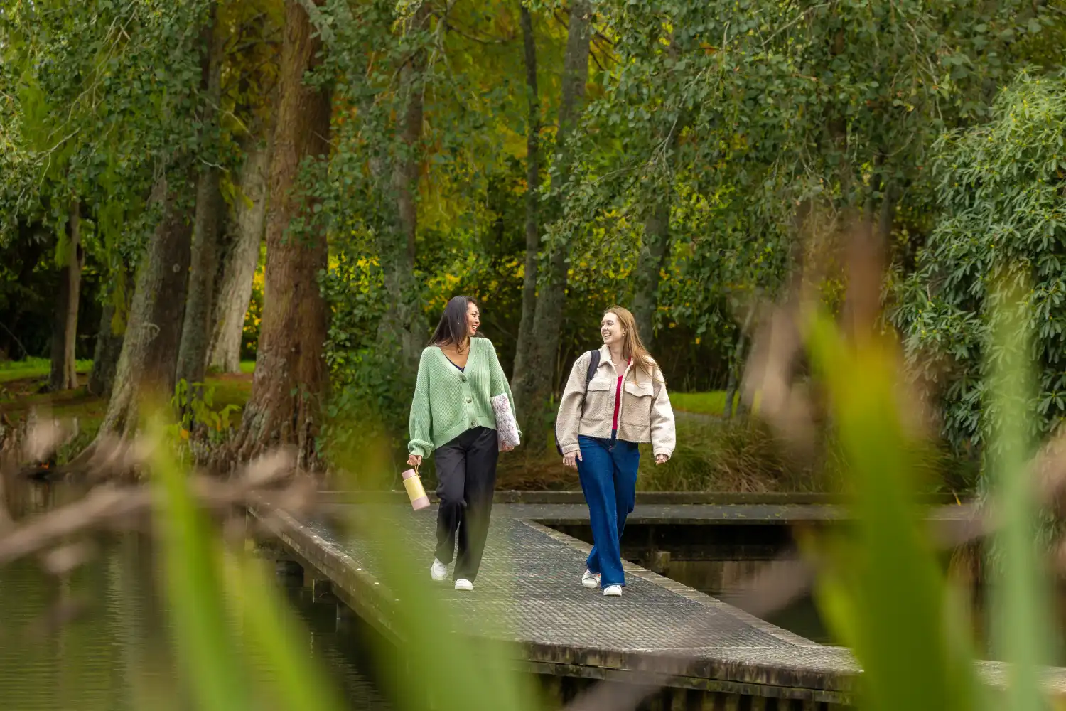 students walking past lake bushes