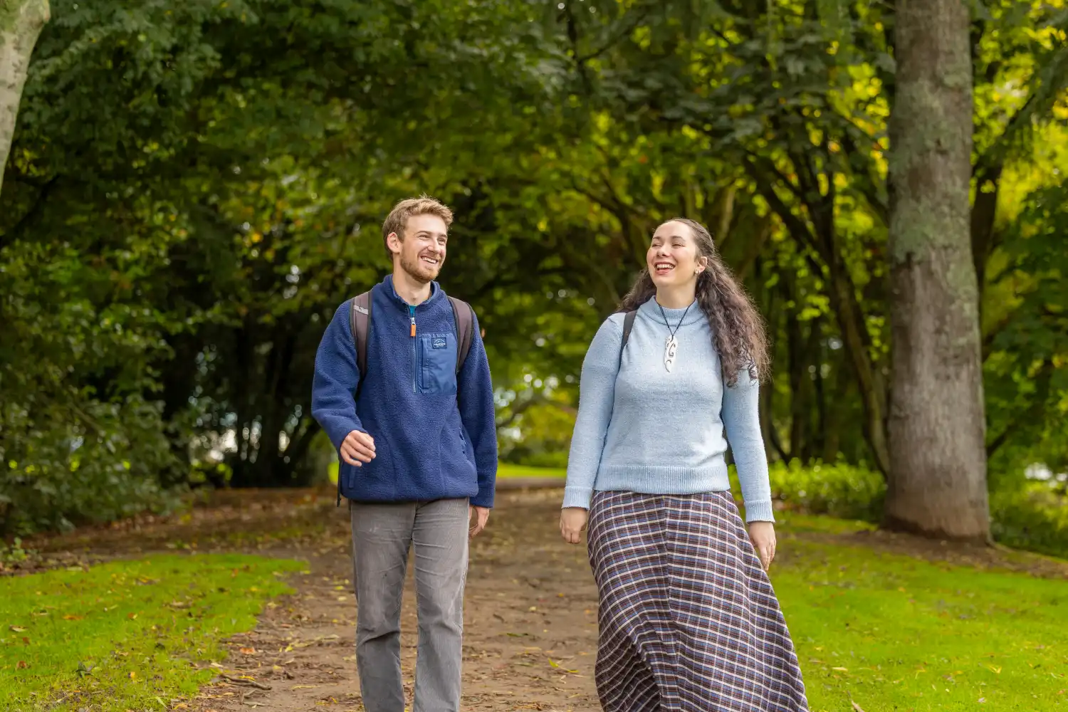 two students walking by trees