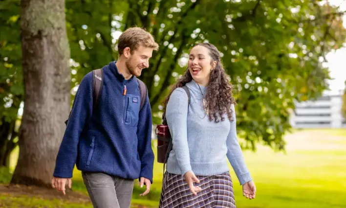 Students walking in the trees on the field