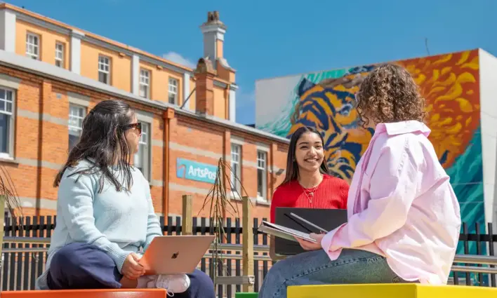 Students sitting outside the museum in front of some art